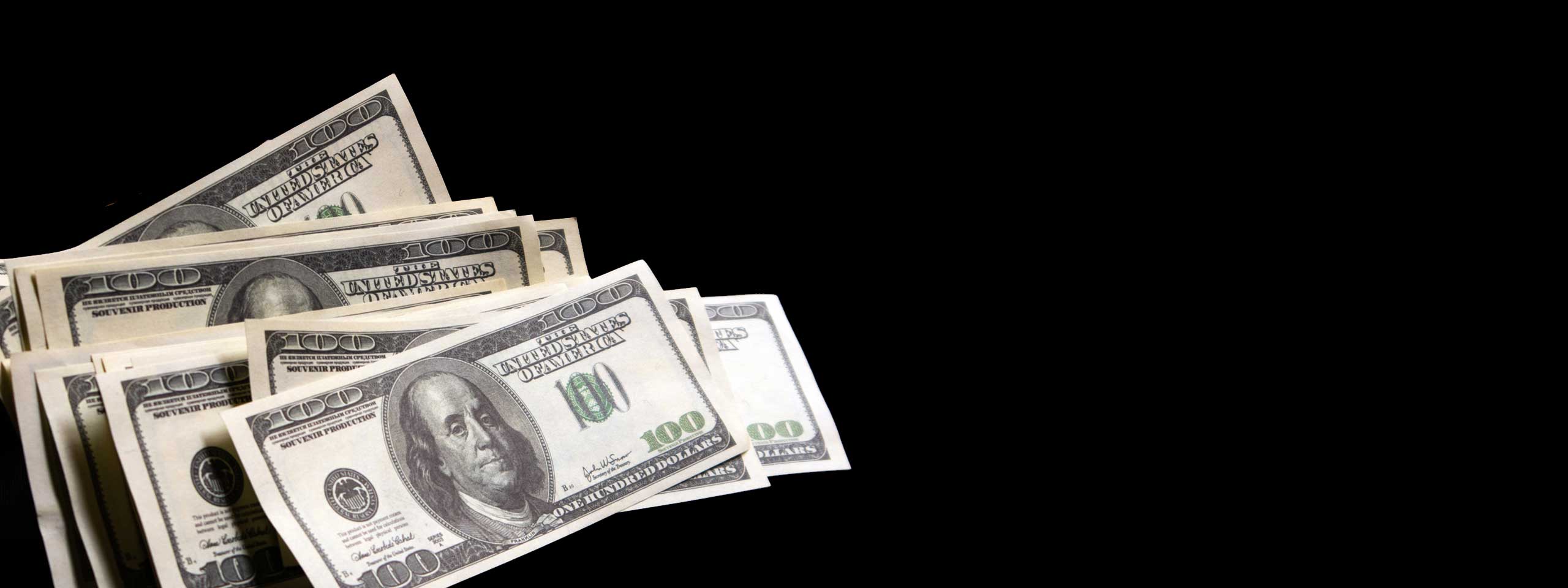 Fanned hundred-dollar bills on a black background
