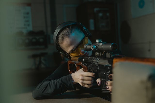 Shooter aiming a scoped rifle at an indoor range